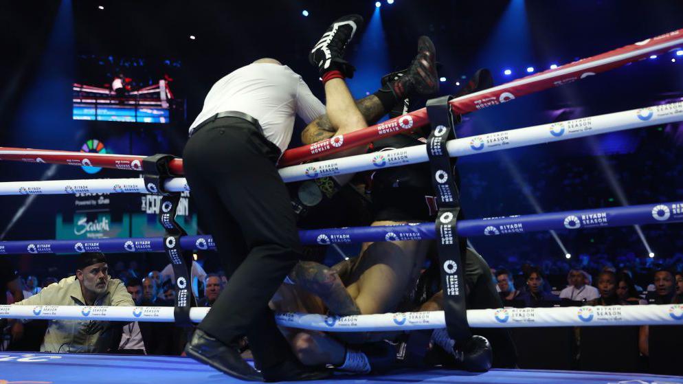 Liam Cameron and Ben Whittaker fall over the ropes during their fight