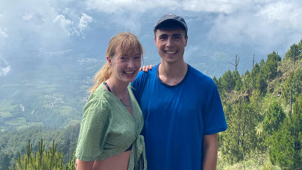 Leila and Louis posing for a photo high up a mountain with the valley behind them