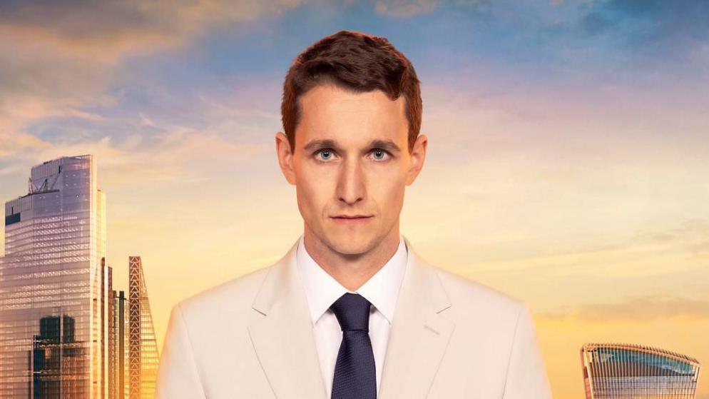 A man with brown hair, a cream suit and black tie stares down the camera. The backdrop is the London skyline. 