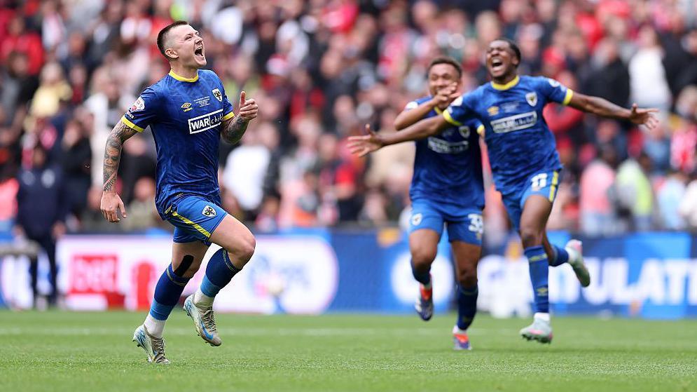 AFC Wimbledon players celebrate after beating Walsall in the League Two play-off final at Wembley