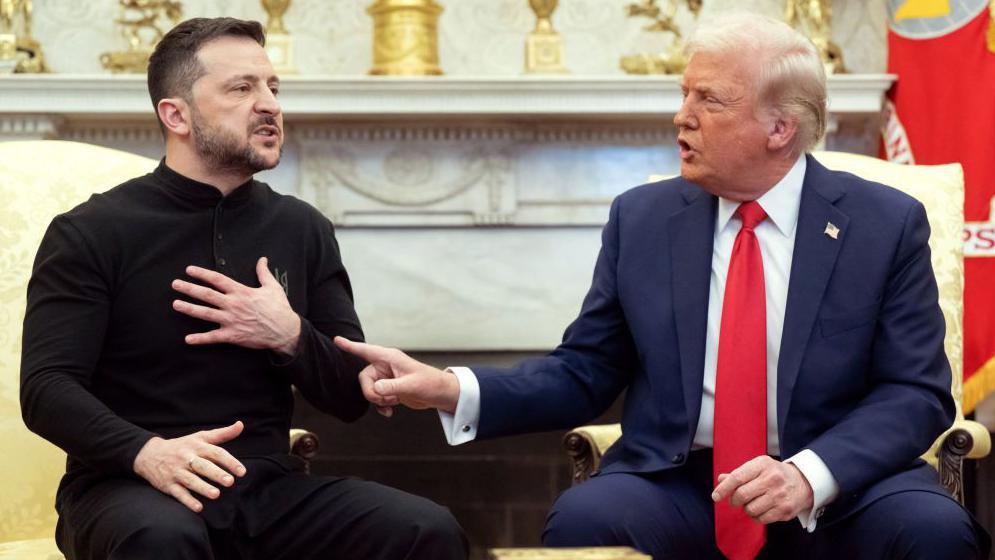 Volodymyr Zelensky sits in the Oval Office with Donald Trump - the two are engaged in an argument, with Trump pointing at the Ukraine leader. Zelensky is dressed in black trousers and a black zipper while Trump wears a blue suit, white shirt and a red tie.