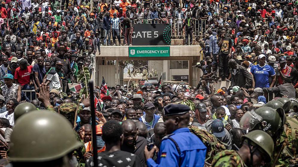 Supporters and mourners jostle and push for space as at an entrance to Nyayo Stadium