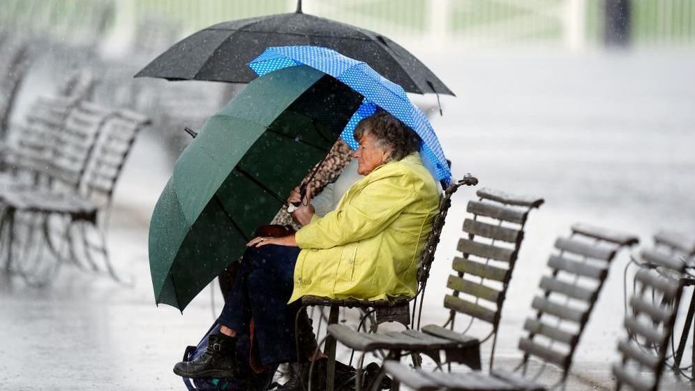 A racegoer shelters from the rain on day one of the Cambridgeshire Meeting at Newmarket Racecourse.