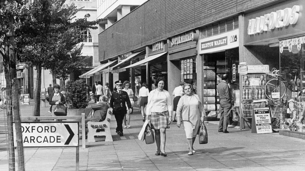 Black and white photo of shoppers in The Hayes in Cardiff city centre in 1971, with shops including Halfords and Lipton