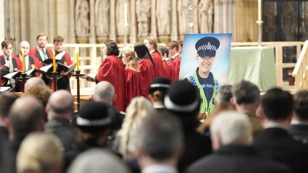 An image of Pc Rosie Prior in police uniform is at the front of York Minster as a congregation watch a choir sing 