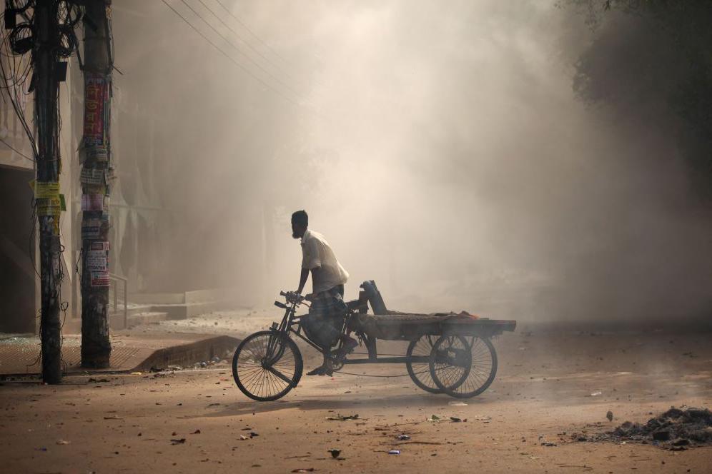 A rickshaw puller is crossing the road when protesters are clashing with police and pro-government supporters after an anti-quota protester is demanding the stepping down of Bangladeshi Prime Minister Sheikh Hasina in the Bangla Motor area, in Dhaka, Bangladesh, on August 4, 2024.