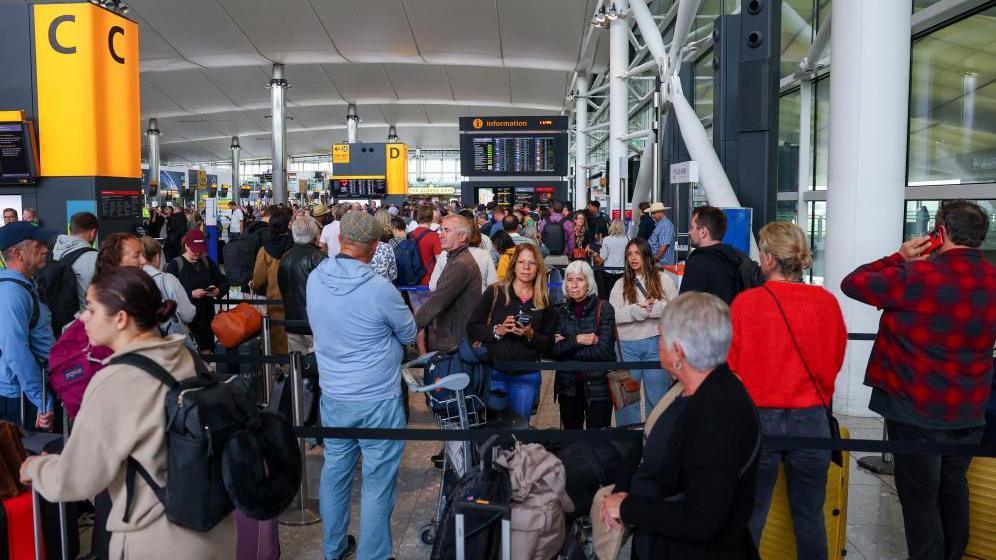 A picture of a check-in area at Heathrow Airport on Saturday morning, filled with busy rows of people queuing up.