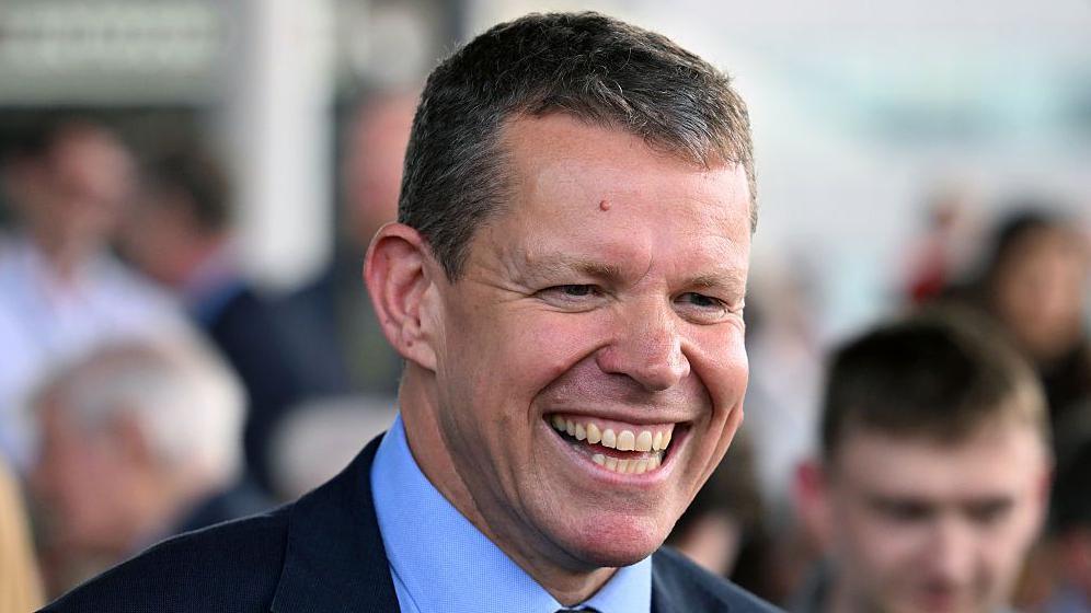Rhun ap Iorwerth yn gwenu gyda chefnogwyr a chyd-Asau Plaid Cymru o'i amgylch ar risiau adeilad y Senedd ddydd Sadwrn