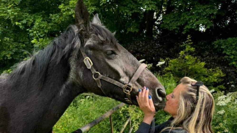 A side-view of Thorne with Sammy holding his mouth and giving him a kiss on the nose