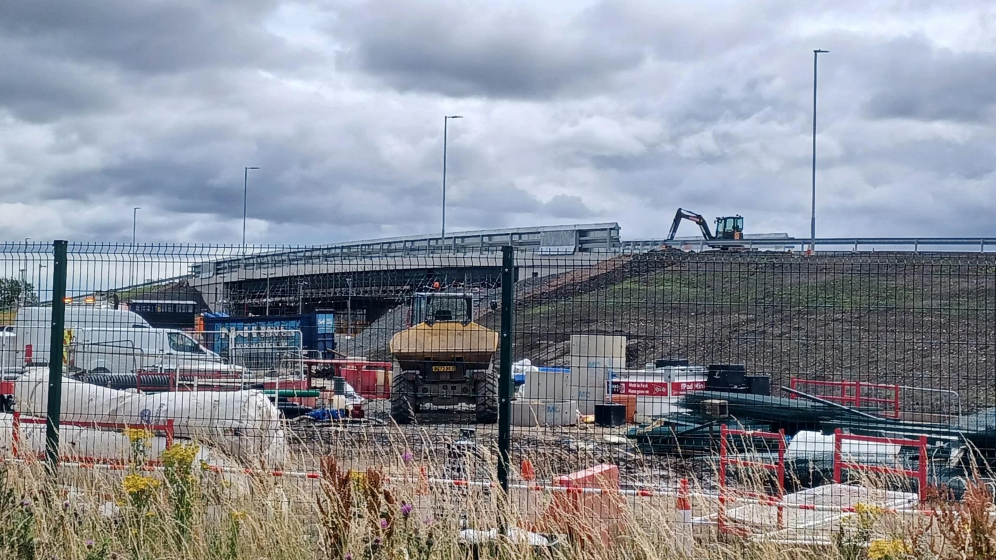 Construction work is happening at a railway station on a new road bridge. 