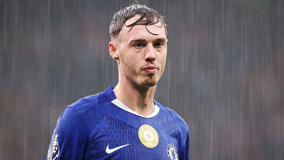 A straight-faced Cole Palmer stands in heavy rain