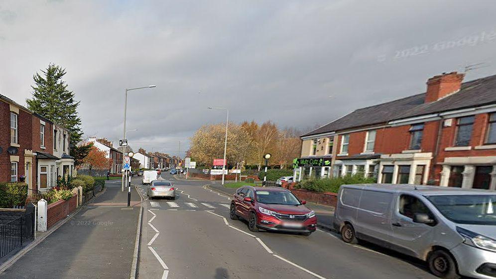 Vehicles driving on Station Road showing a pelican crossing 