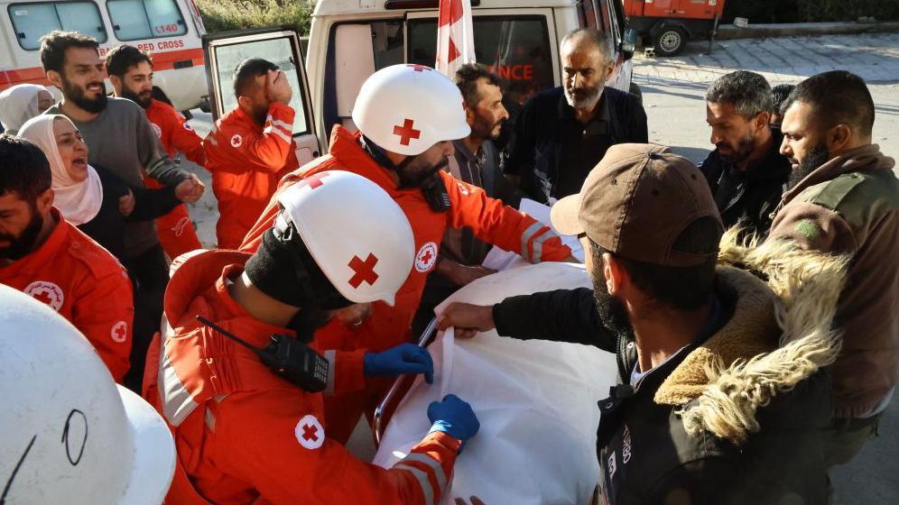 Relatives of a person who died in an attack carried out by the Israeli army in the town of Shebaa in southern Lebanon mourn as the person lies on a stretcher surrounding by medical workers in orange uniforms