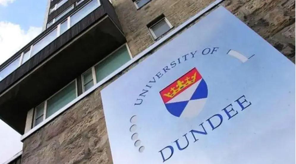 A large silver sign with a crest and the words University of Dundee attached to a stone building