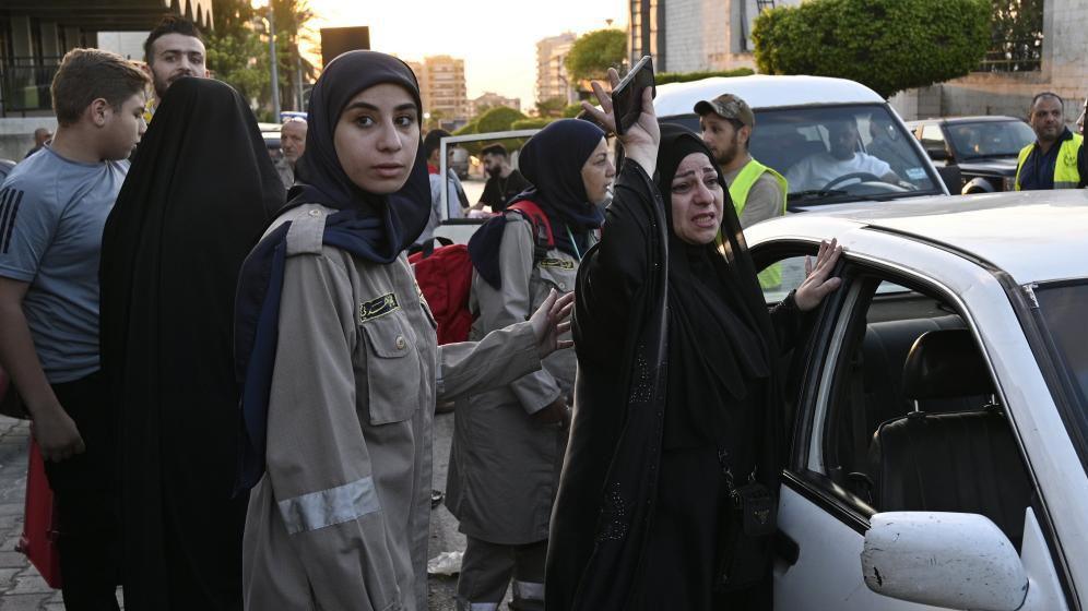 civil defense employee comforts woman who fled southern lebanon, in beirut