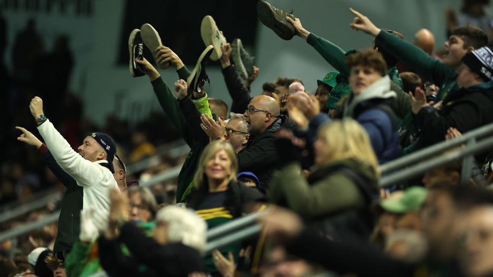 Northampton Saints fans hold their shoes in the air