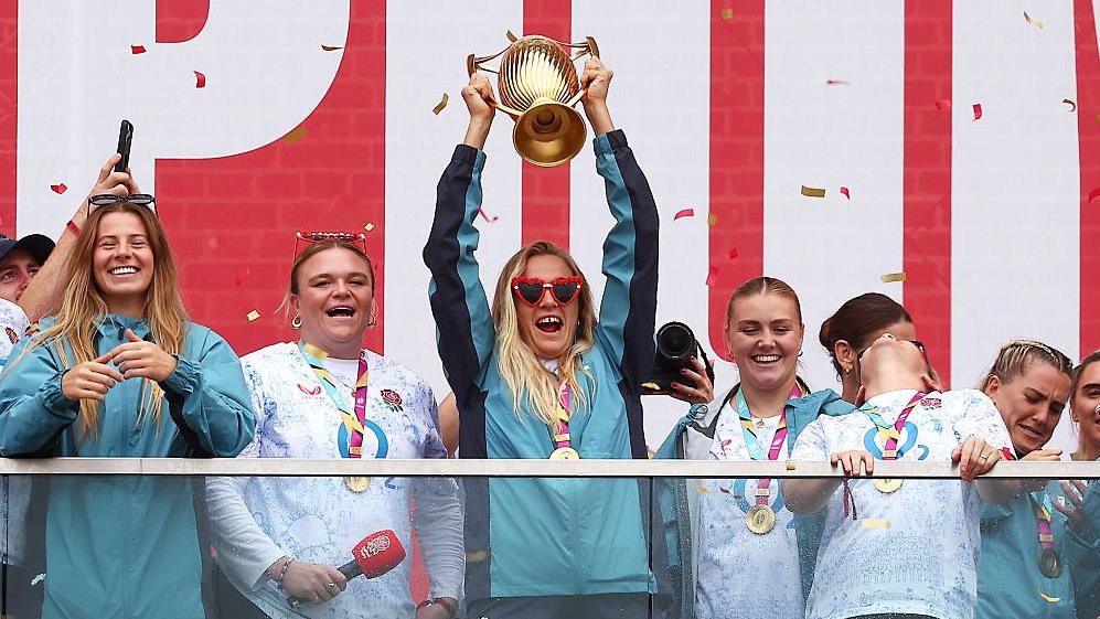 Zoe Aldcroft lifts the Women's World Cup trophy as she celebrates with team-mates at Battersea Power Station 