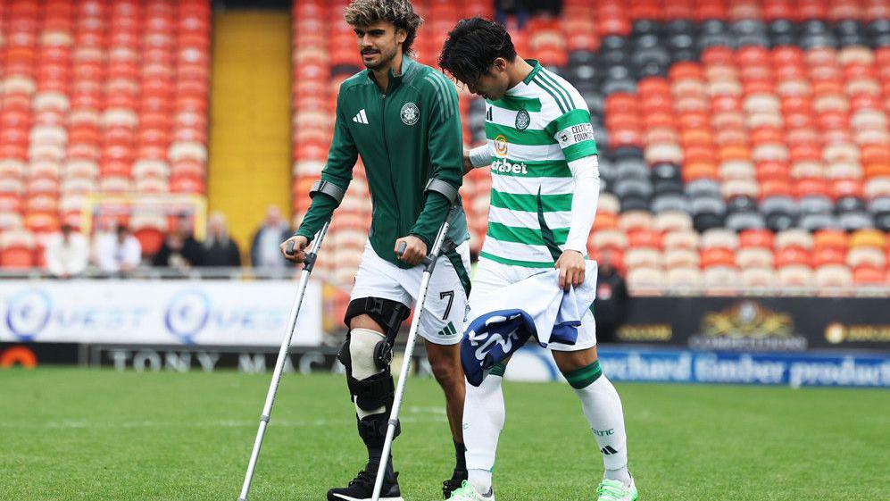 Celtic's Jota on crutches at Tannadice, accompanied by Reo Hatate