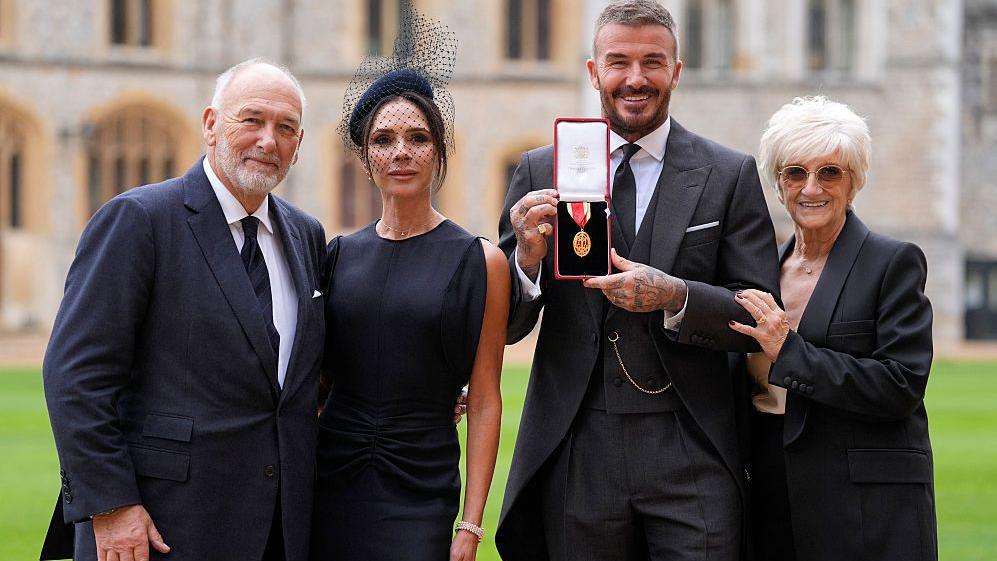 David Beckham poses next to his wife Victoria Beckham and his parents Ted and Sandra