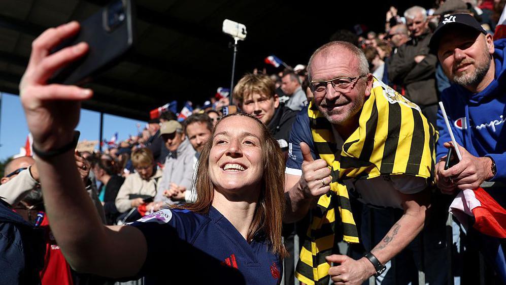 Pauline Bourdon-Sansus takes a selfie with a fan