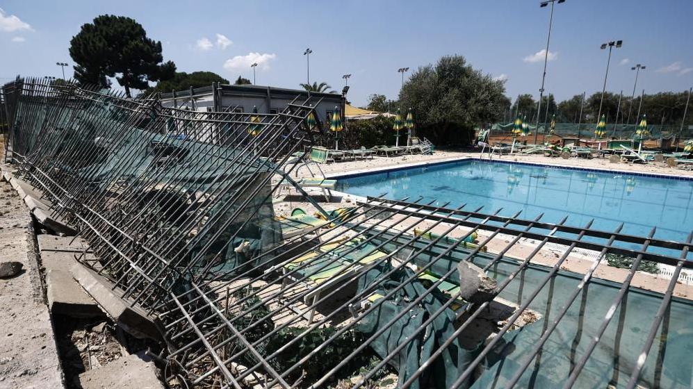 Picture shows damage to a nearby sports centre after the explosion. The roof is completely shattered and there is debris scattered around a swimming pool