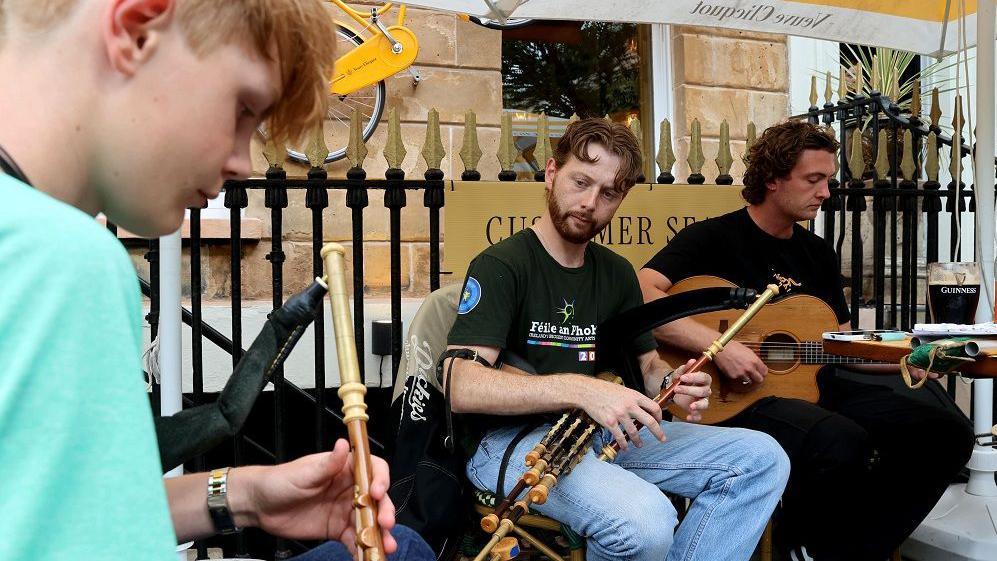 Three young men, playing instruments on the street