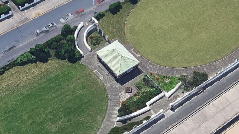 An aerial view of a one-storey building with a green roof, surrounded by a pathway and two grassy areas.