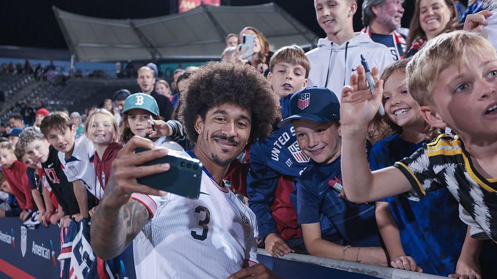 USA player Chris Richards poses for a selfie with fans at a match 