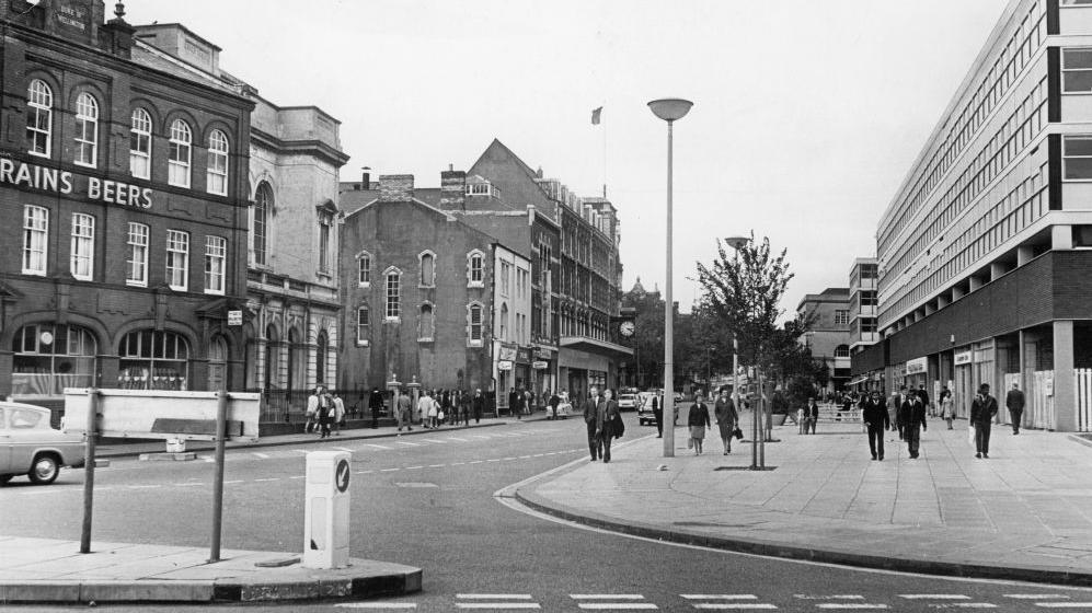 A black and white photo of The Hayes in Cardiff in 1970, with a Brains beer building on the left, a road in the middle and buildings on the right and at the rear