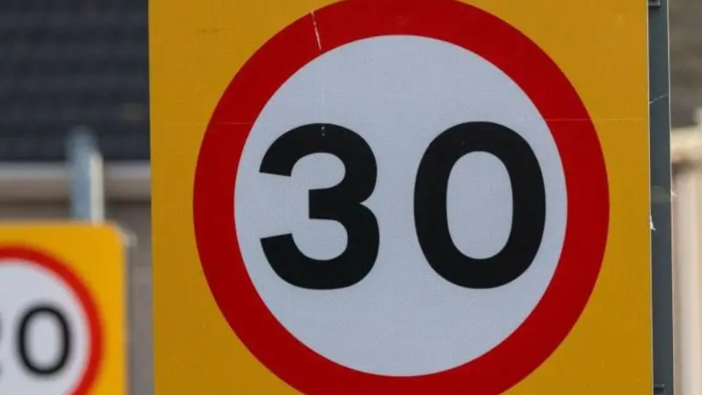 A photo of a 30 mile per hour yellow sign red and black sign. 
