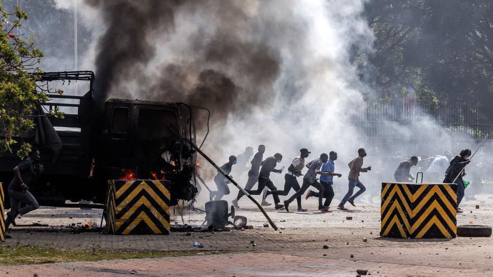 Protesters run to take cover outside the Kenyan Parliament after storming the building during a nationwide strike to protest against tax hikes and the Finance Bill 2024 in downtown Nairobi, on June 25, 2024