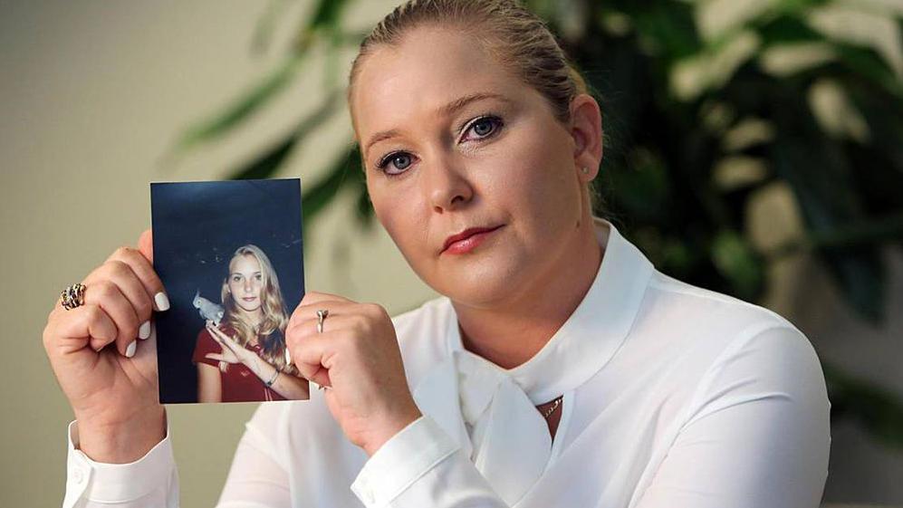 Virginia Giuffre holding a picture of herself as a teenager