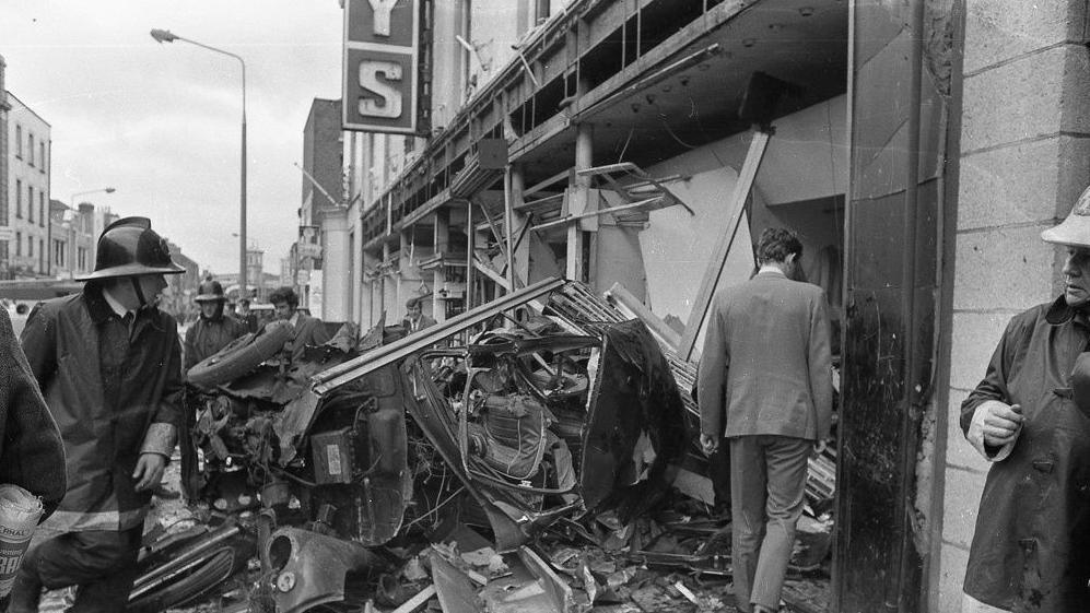 Firemen examine wreckage after Dublin bomb