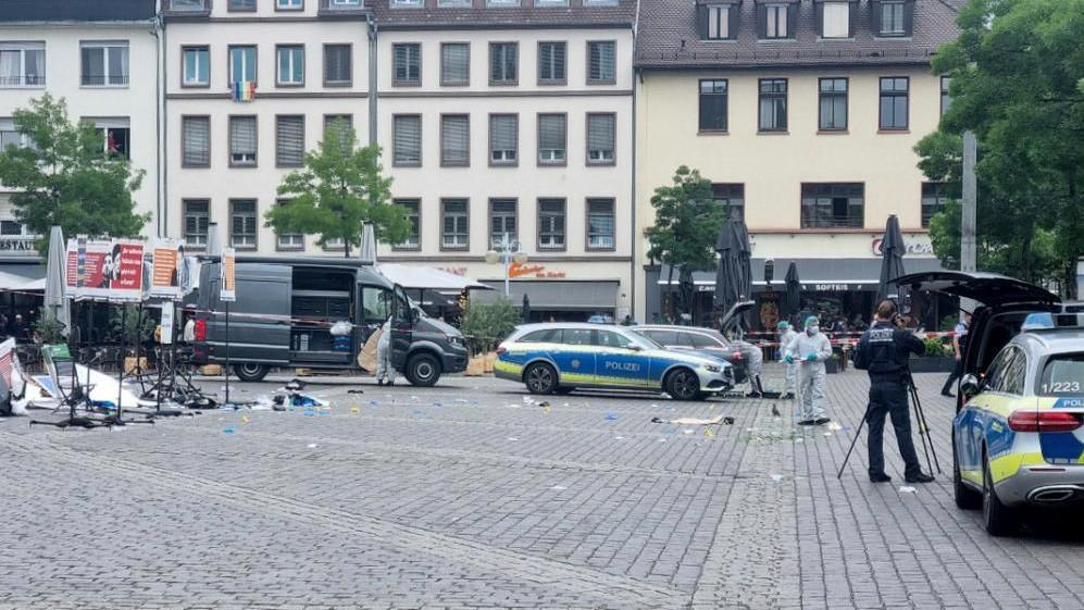 Debris on ground of market with microphone stands and police vehicles 