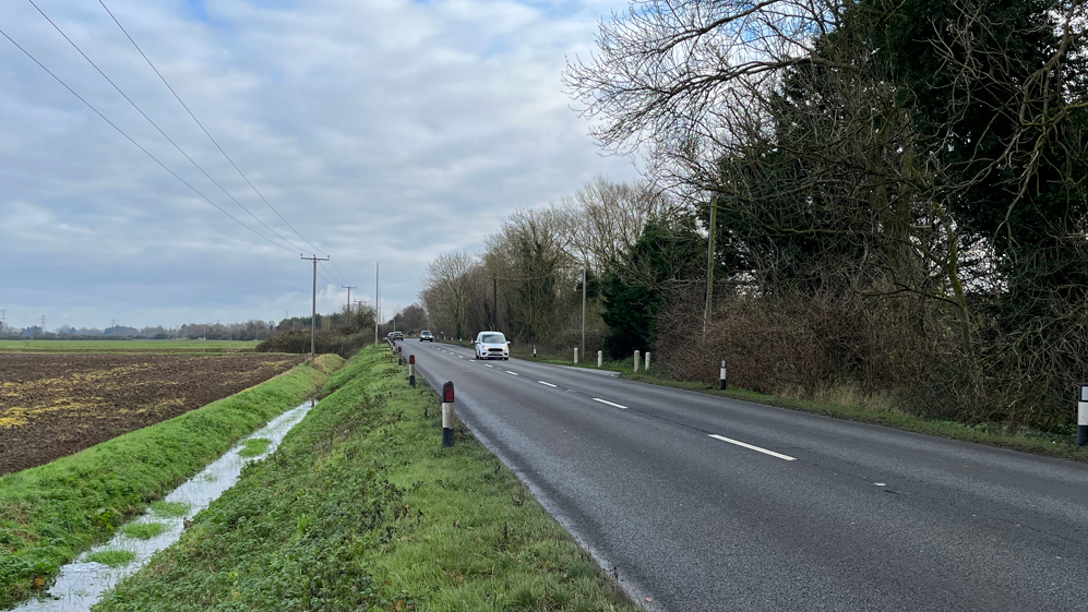 Pullover Road, which is where the man's body was found. It is a two-lane road with trees overhanging it on one side and a ditch next to farmland on the other
