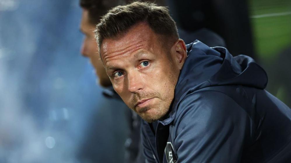 Assistant manager Craig Bellamy sits in the Burnley dug-out