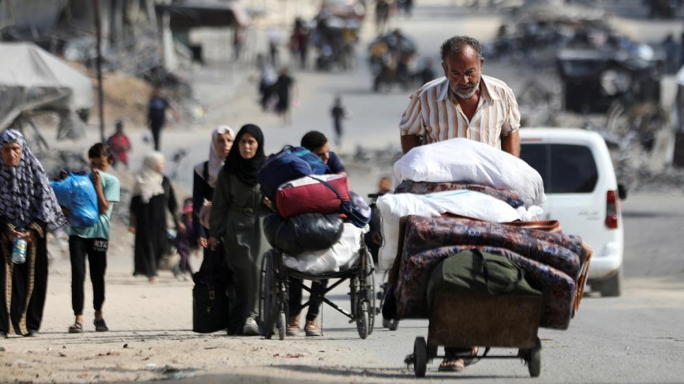 A man pushes a cart carrying belongings in Gaza City as he flees northern Gaza on 12 Oct