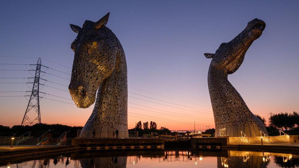 The Kelpie statues with a sunset in the background.