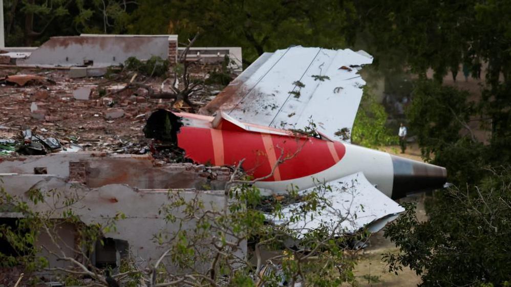 The tail of an Air India Boeing 787 Dreamliner is seen lodged in a building after the crash in Ahmedabad