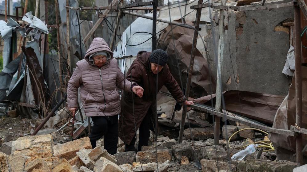 Elderly women pick their way through rubble in Odesa