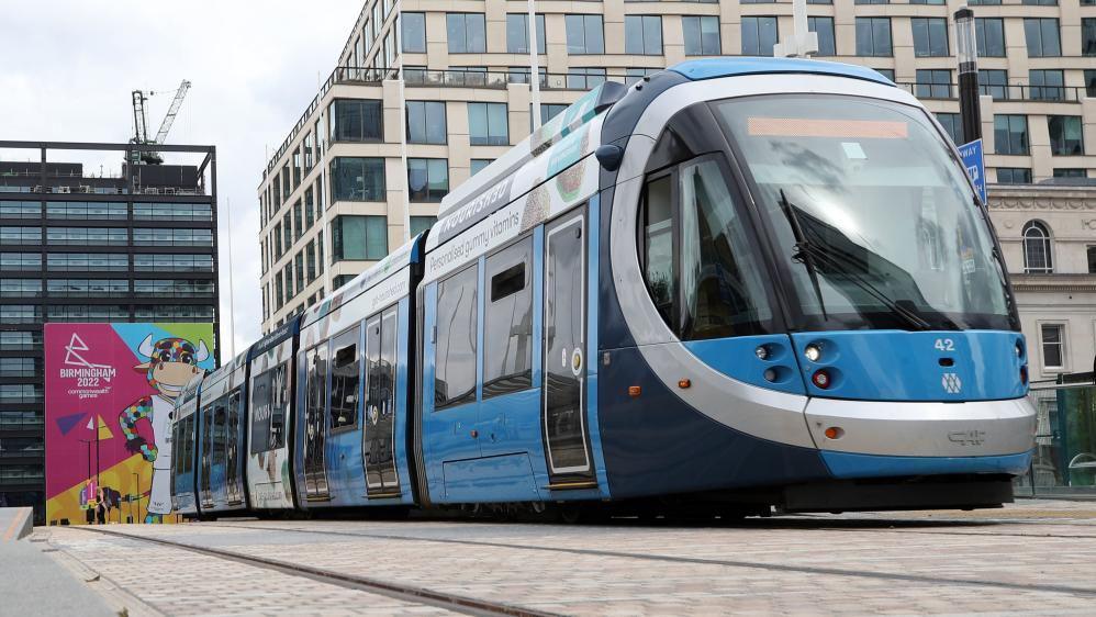 A blue and silver tram in a city centre. 