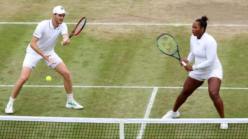 Jamie Murray and Taylor Townsend standing at the net during a point as a ball comes over the net