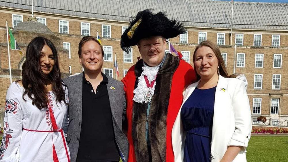 Three people standing outside the council offices with the Lord Mayor who is wearing full regalia