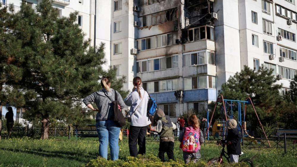 Locals stand at the site of a Russian drone strike, amid Russia's attack on Ukraine, in the city of Chornomorsk, Odesa region, Ukraine October 8