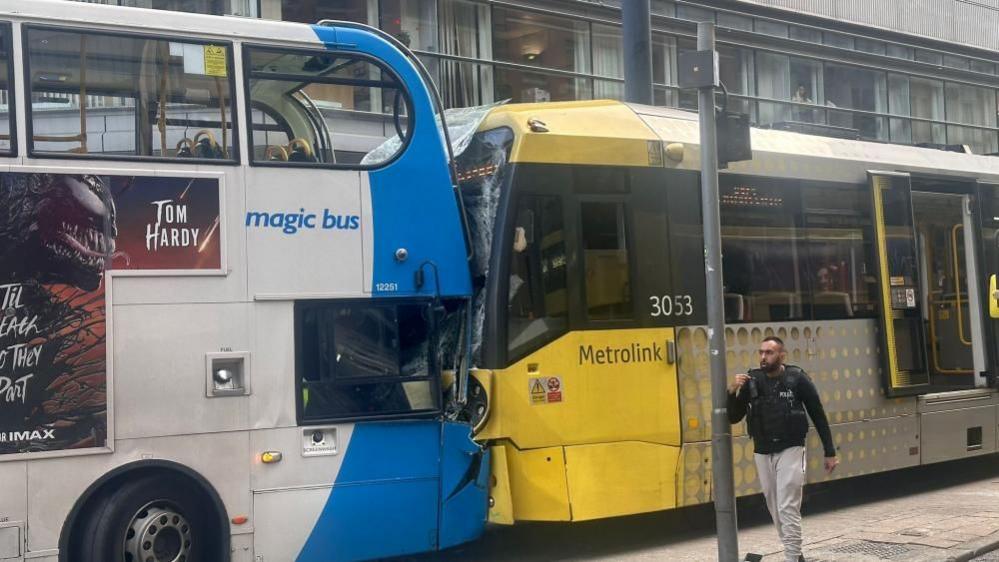 A bus and a tram are both stationary after having crashed into each other head-on. Both have smashed front windscreens