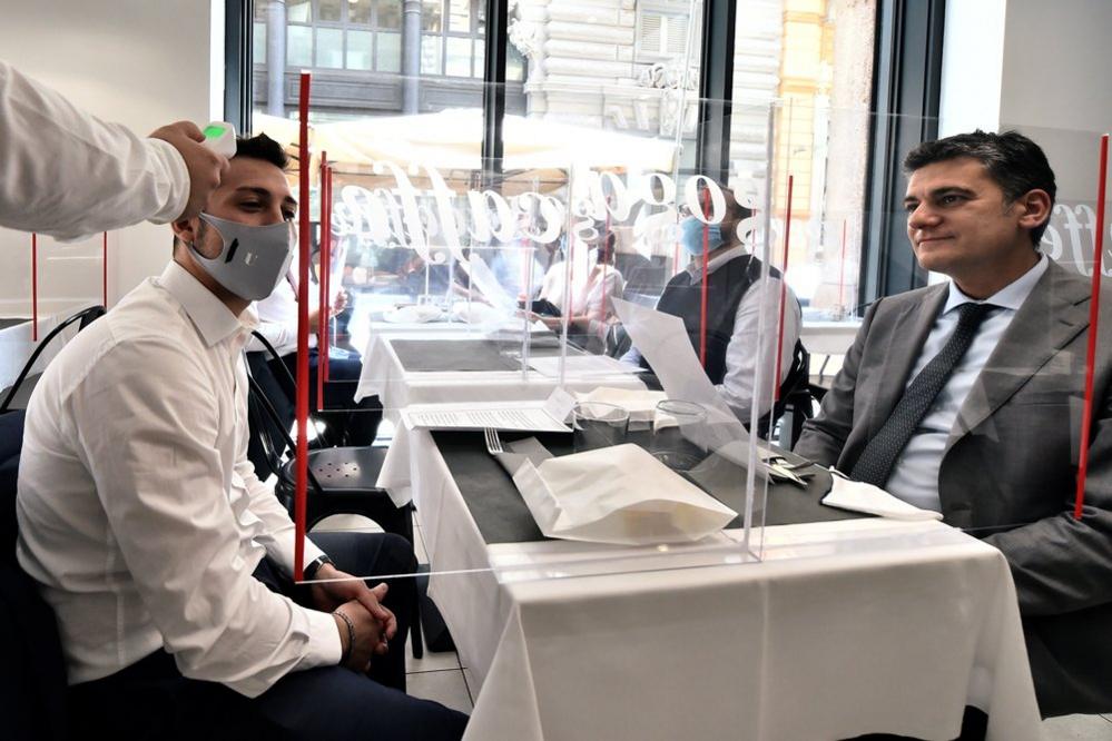 A waiter checks a customer's temperature in a restaurant