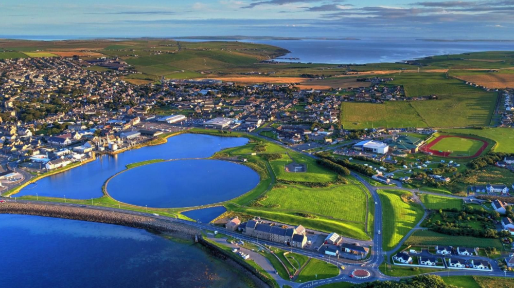 An aerial view of Orkney showing roads, green landscape and a running track.