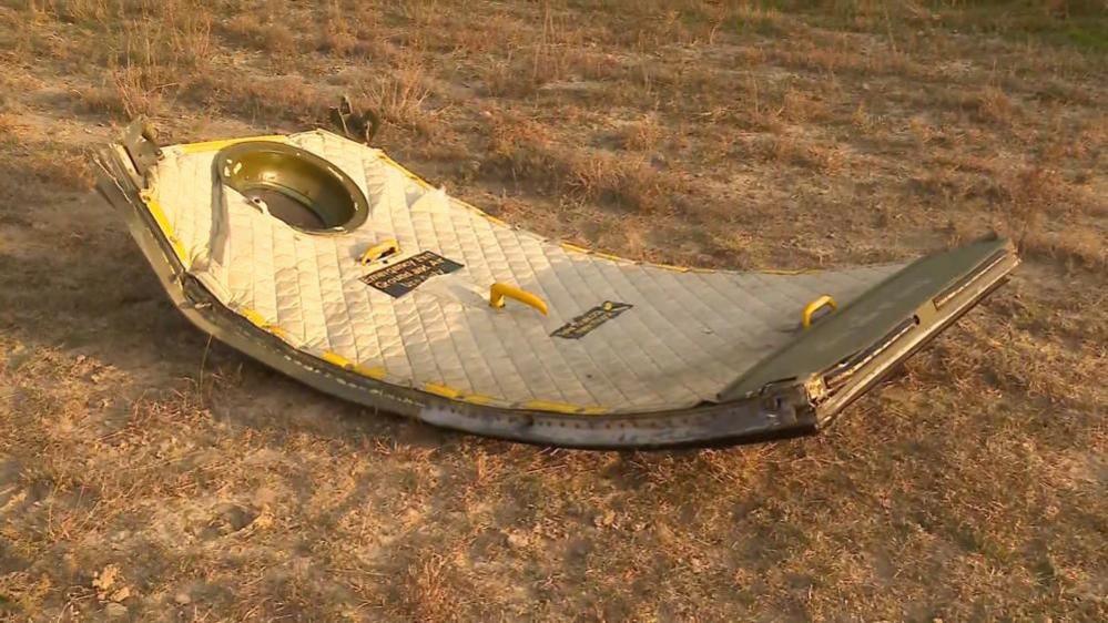 A plane's door on the ground as part of what appears to be wreckage of the plane