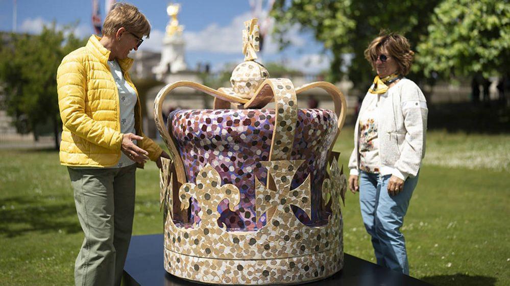 two women looking at giant painted crown