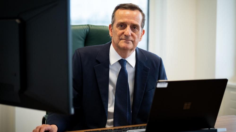 Stephen Parkinson sits at his desk